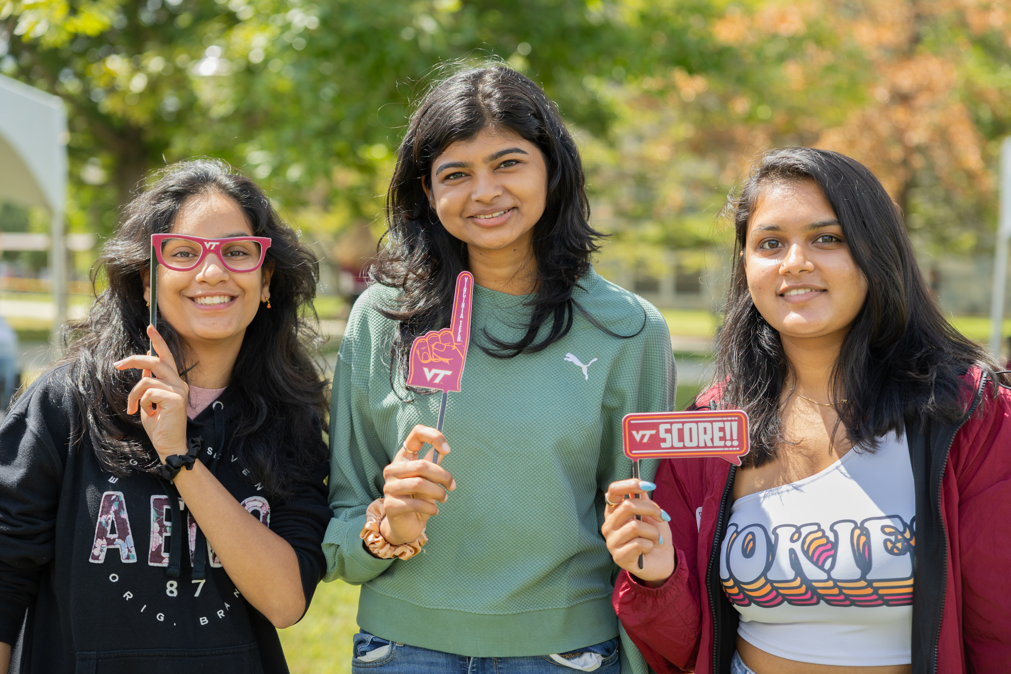 Three Virginia Tech ECE students smile and pose at a tailgate.