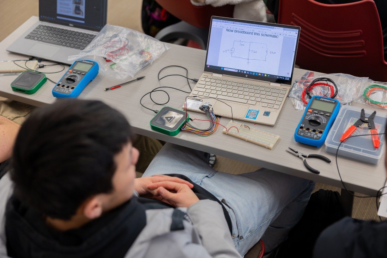 Zoomed out view of a student's laptop with the AD3 set up around them.