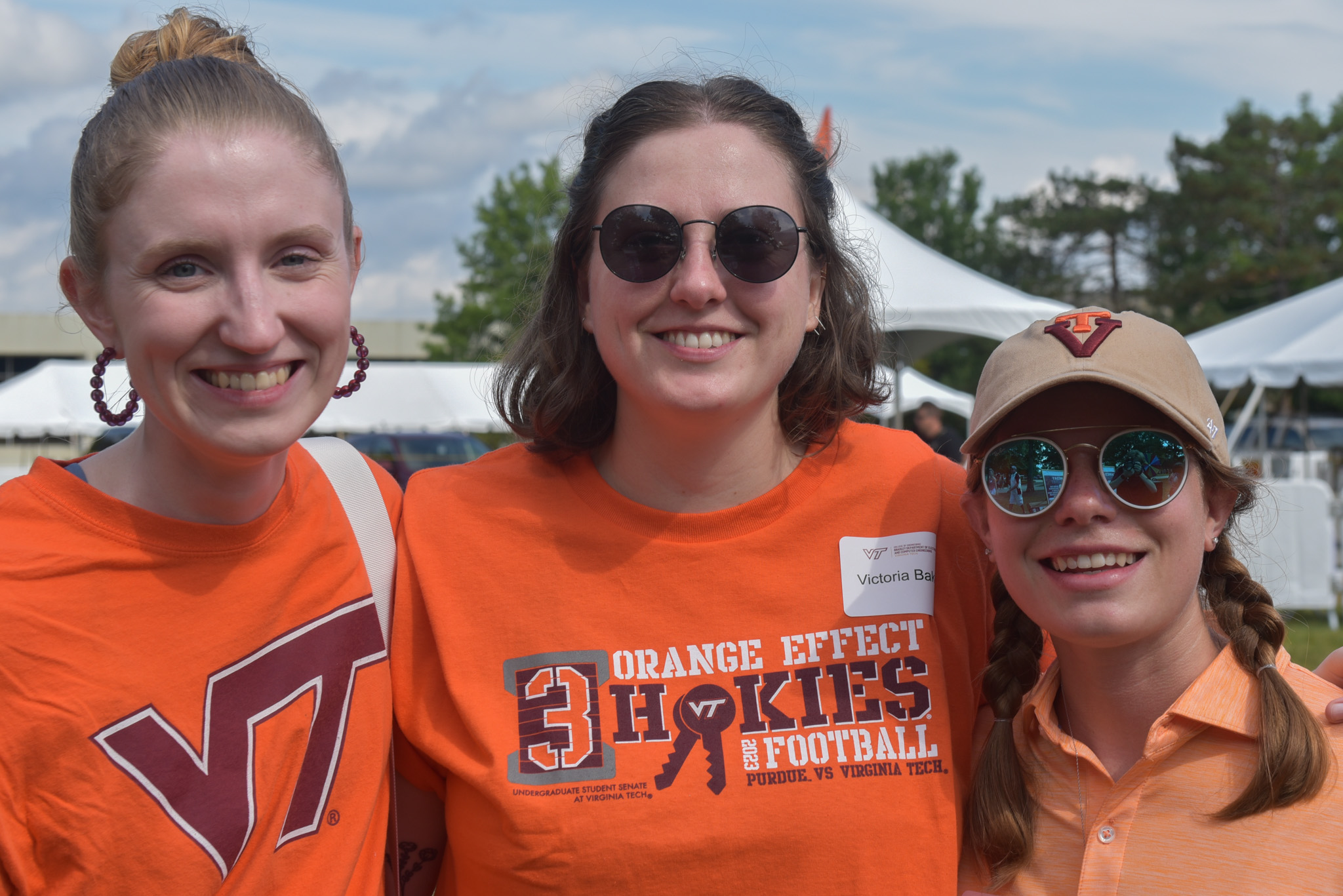 Three Virginia Tech ECE alumni smile at a tailgate.