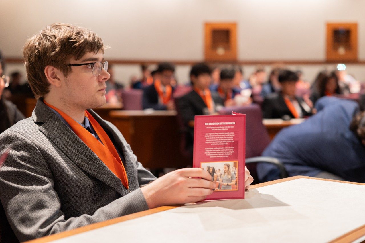 An ECE student wears his new HLB medal while holding the HLB pamphlet.