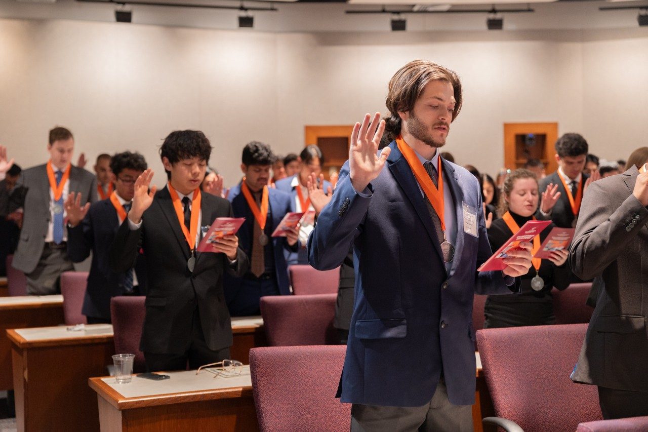 A group of ECE students raise their hands for the Heta Lambda Beta (HLB) ceremony.