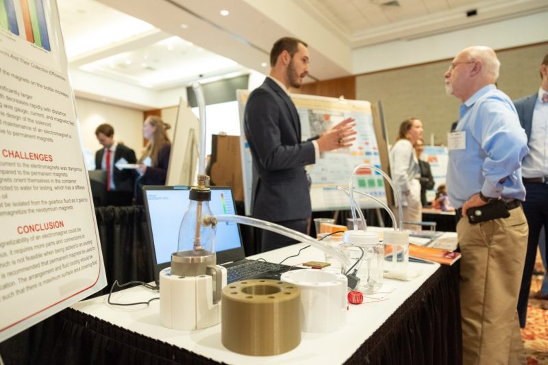 Student presenting poster to industry partner at table during MDE expo at the Inn at Virginia Tech