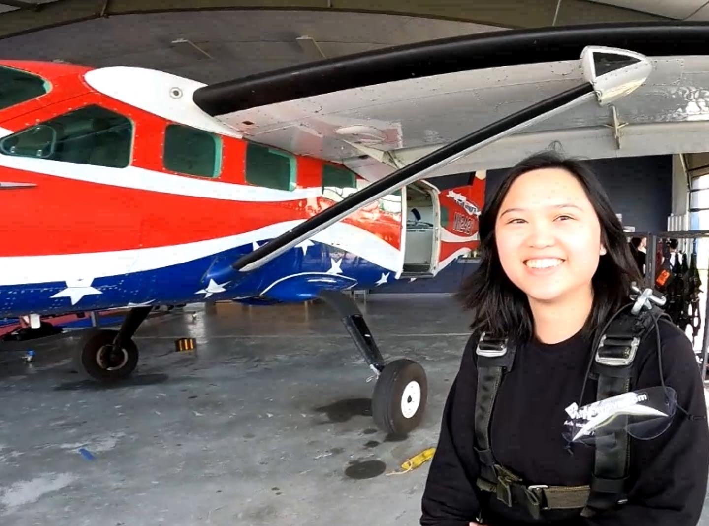A woman smiles next to a patriotic airplane