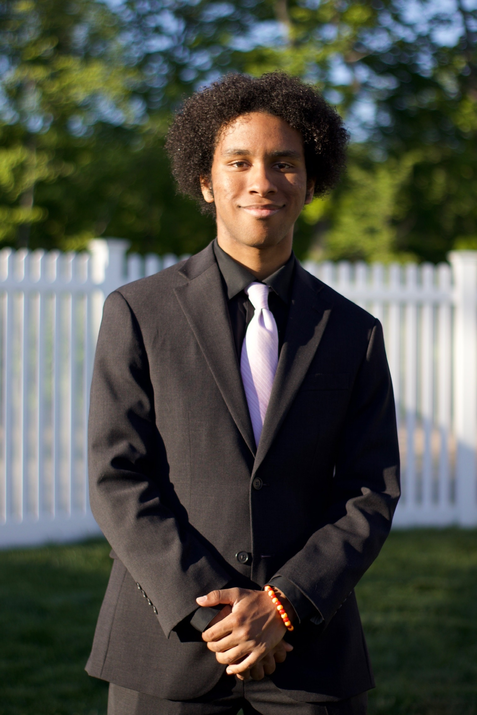 A man in a suit with a purple tie stands outside