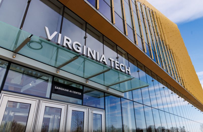 a long glass building reflecting the blue sky